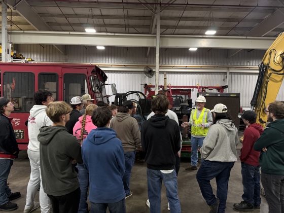 JCTC students gather by a red vehicle to listen to an R. J. Corman employee on their guided tour.