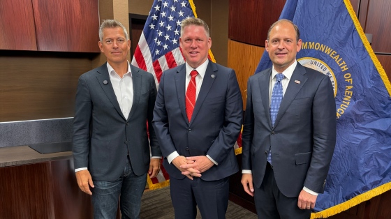 Justin Broyles stands with Andy Barr and Sean Duffy in front of the American and Kentucky flags.